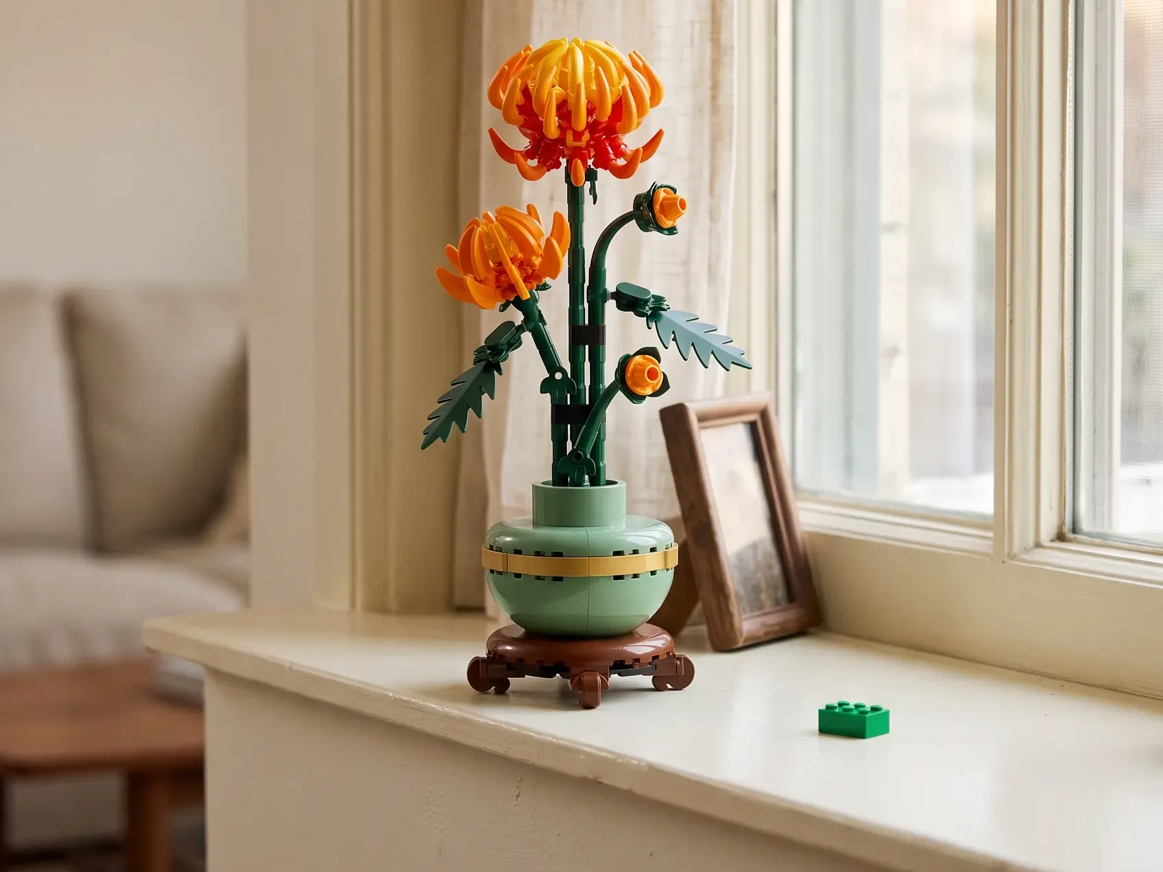 Finished LEGO chrysanthemum flower in its own green pot on a windowsill with a few spare bricks beside it, a building gift for homebodies