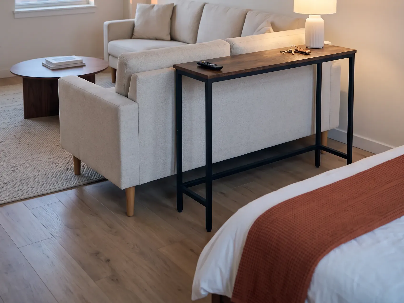 Narrow console table standing behind a sofa in a studio apartment, one of the studio apartment ideas for marking a living zone