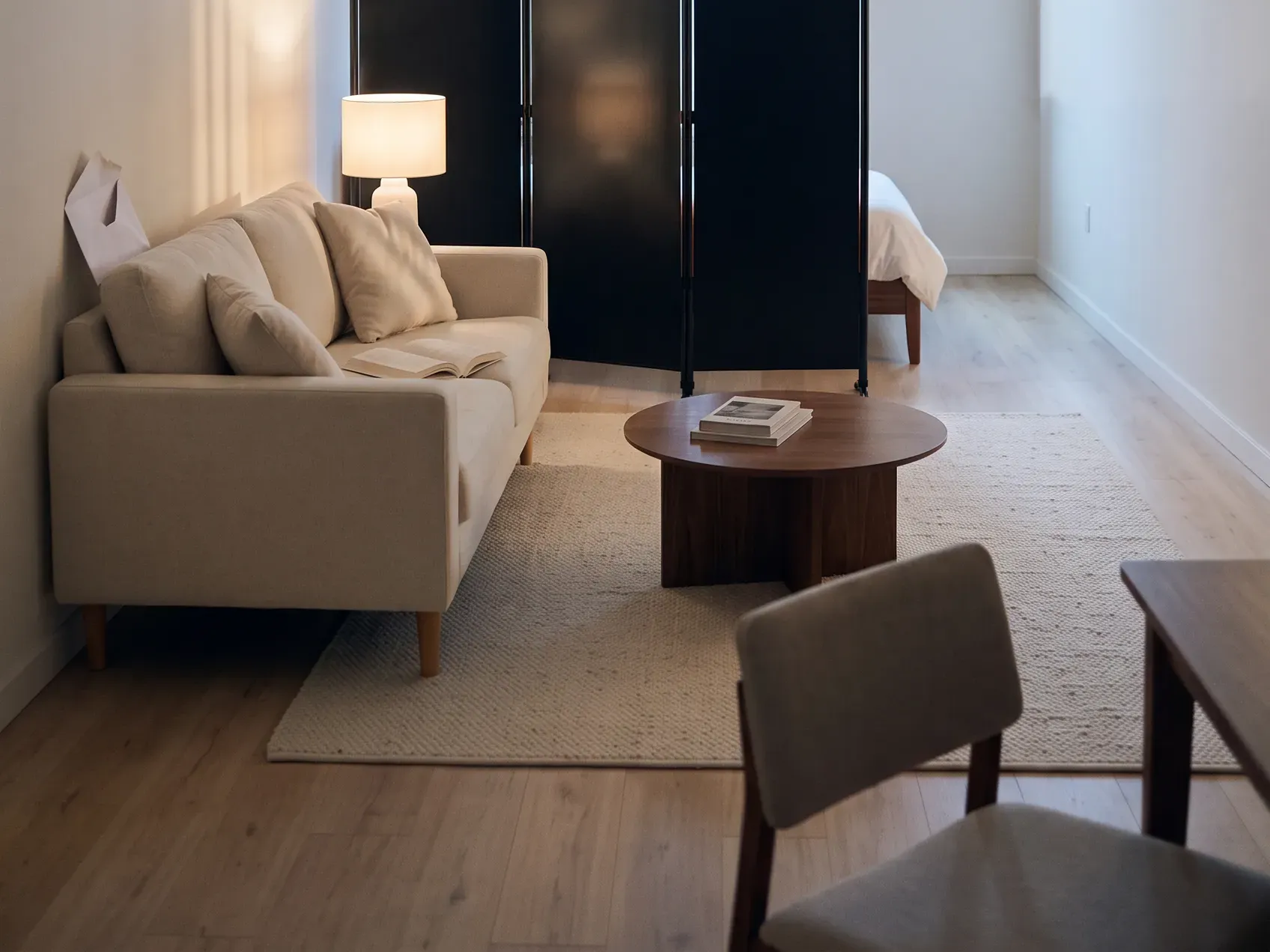 Studio apartment seen from the doorway with a folding screen angled away from the entrance and a clear sightline to the window, studio apartment ideas that keep one room feeling open
